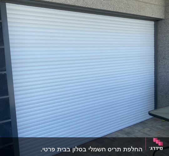 תריס גלילה לבן סגור על קיר חיצוני